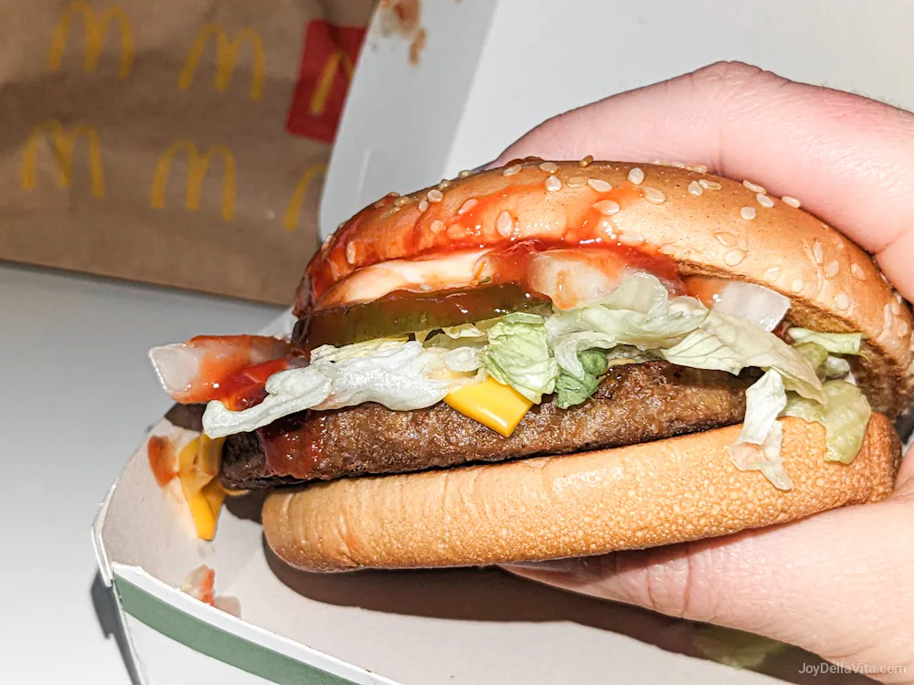 vegetarischer, pflanzlicher McPlant Burger in der Hand mit Verpackung im Hintergrund